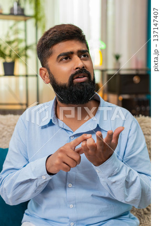 Indian man counts tasks on fingers thinking life decisions serious focus indoors reflective moment 137147407