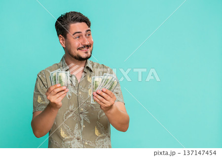 Man counting cash dollars money with satisfied smile expressing financial gain recent income savings Man counting cash dollars money with satisfied smile expressing financial gain recent income savings 137147454