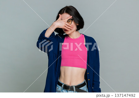 Woman playfully spying through hand shaped like binoculars smiling humorously indicating curiosity Woman playfully spying through hand shaped like binoculars smiling humorously indicating curiosity 137147492