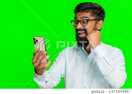 Indian man holding smartphone looking excited celebrating win jackpot lottery mobile game happy news Indian man holding smartphone looking excited celebrating win jackpot lottery mobile game happy news 137147494