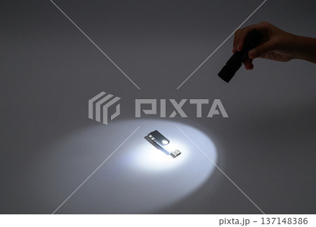 暗闇でUSBメモリを懐中電灯で照らす様子 137148386