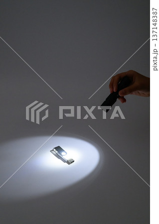 暗闇でUSBメモリを懐中電灯で照らす手元 137148387