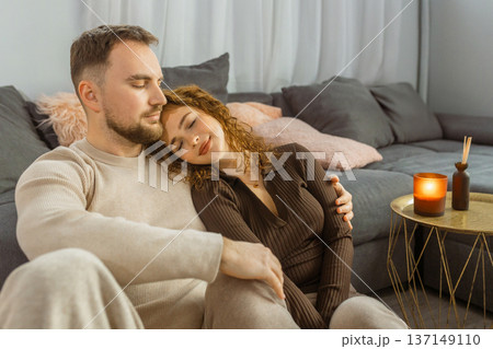 Happy couple cuddling on sofa at home romantic evening lifestyle Happy couple cuddling on sofa at home romantic evening lifestyle 137149110