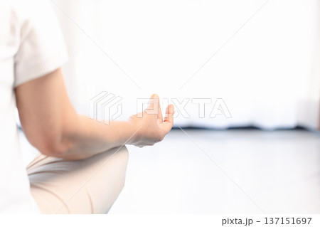 Close-up of hands in yoga meditation mudra during mindfulness practice, soft bright background with copy space. Calm wellness concept for relaxation, breathing, zen and mental health. 137151697