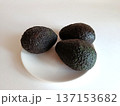 Three ripe hass avocados with dark green, bumpy skin resting on a white plate, highlighting a healthy diet, fresh nutrition, and natural food ingredients 137153682