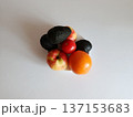 Fresh assortment of vibrant fruits and a red tomato, including avocados, apples, and an orange, presenting a healthy eating concept from a top view on a white background 137153683