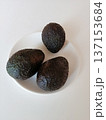 Three ripe hass avocados resting on a white plate, presenting a simple and clean composition with healthy fats, fresh produce, and a focus on wellness nutrition 137153684