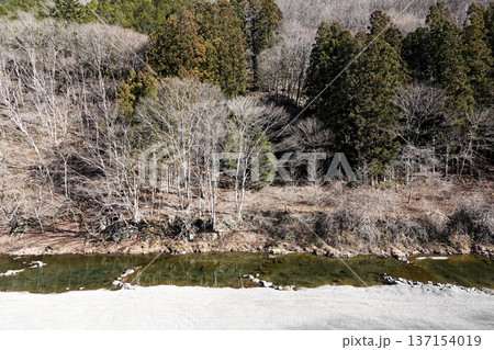 渓谷を緩やかに流れる川と対岸の冬の樹木 137154019