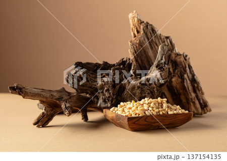 Pine nuts in wooden dish on a beige background. Pine nuts in wooden dish on a beige background. 137154135