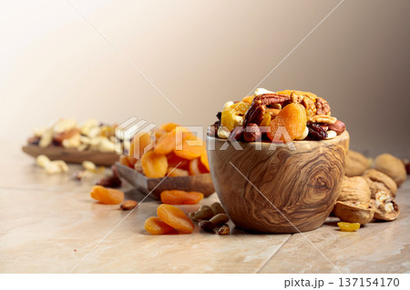 Dried fruits and nuts on a beige ceramic table. Dried fruits and nuts on a beige ceramic table. 137154170