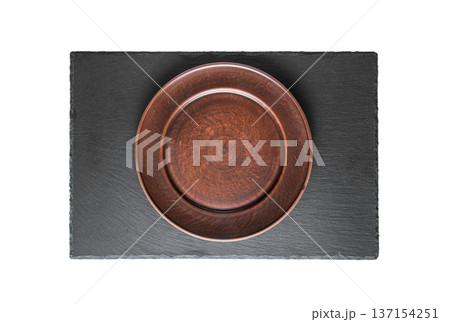 Empty rustic brown ceramic plate placed on black slate serving board 137154251