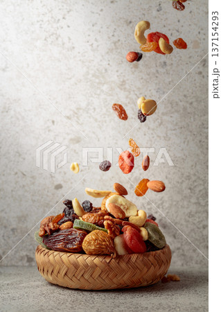 Mix of dried fruits and nuts in motion on a gray background. Mix of dried fruits and nuts in motion on a gray background. 137154293