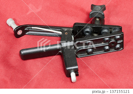 Sturdy photographic studio clamp against a red background Sturdy photographic studio clamp against a red background 137155121