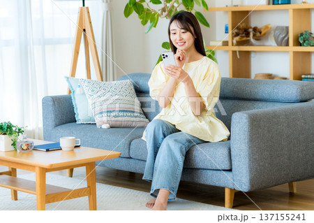 部屋でスマホを操作する女性 137155241