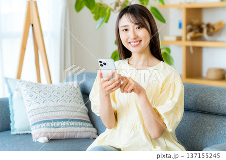 部屋でスマホを操作する女性 137155245