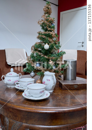 Artificial Christmas tree placed on a round living room table with a tea set Artificial Christmas tree placed on a round living room table with a tea set 137155336