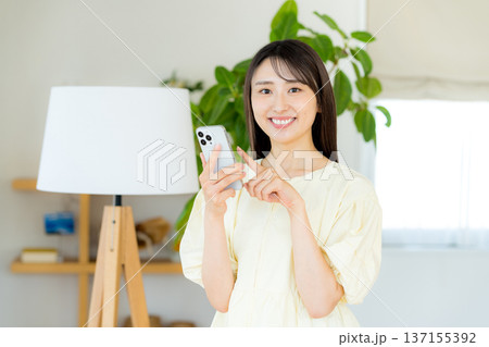 部屋でスマホを操作する女性 137155392