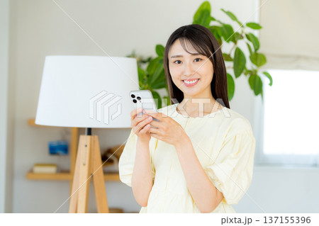 部屋でスマホを操作する女性 部屋でスマホを操作する女性 137155396