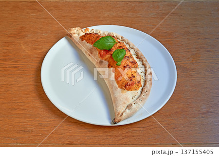 Pizza Calzone on white plat on wooden table 137155405