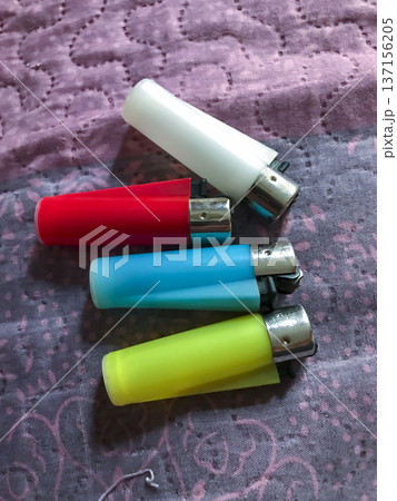 four colored lighters, blue,red,yellow and white on a cloth four colored lighters, blue,red,yellow and white on a cloth 137156205