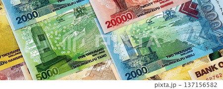 Ugandan shilling paper banknotes pile on table. Uganda UGX currency money bills in big amount. Concept of economics, taxation and banking in Uganda Ugandan shilling paper banknotes pile on table. Uganda UGX currency money bills in big amount. Concept of economics, taxation and banking in Uganda 137156582