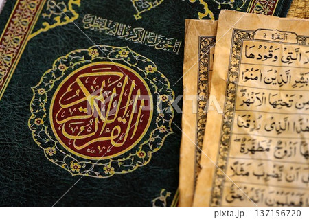 Al Quran Muslim holy book on table in mosque. Details of arabic calligraphy on islamic book cover close up. Concept of Islam religion and praying in arabic countries 137156720