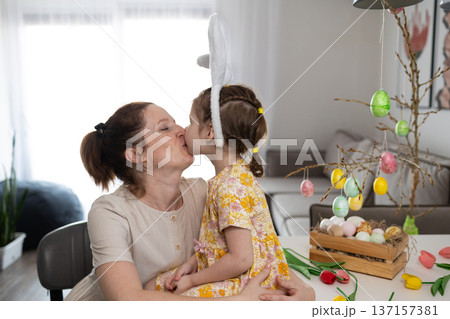 Mother and Daughter Share a Loving Kiss While Decorating for Easter Mother and Daughter Share a Loving Kiss While Decorating for Easter 137157381
