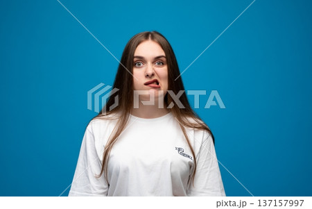 Young woman grimacing, pulling a silly face with her tongue twisted while looking at the camera, conveying confusion and humor Young woman grimacing, pulling a silly face with her tongue twisted while looking at the camera, conveying confusion and humor 137157997
