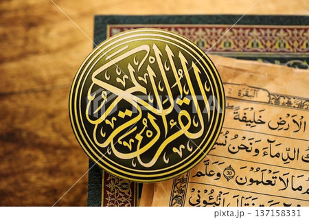 Sign with Al Quran inscription on Muslim holy book in mosque. Details of arabic calligraphy on sticker. Concept of Islam religion and praying in arabic countries Sign with Al Quran inscription on Muslim holy book in mosque. Details of arabic calligraphy on sticker. Concept of Islam religion and praying in arabic countries 137158331
