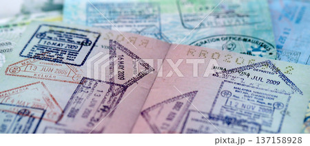 Big amount of passport pages full of colorful stamps after travel and border crossing. Tourism and border control concept. Immigration and travel around the world Big amount of passport pages full of colorful stamps after travel and border crossing. Tourism and border control concept. Immigration and travel around the world 137158928