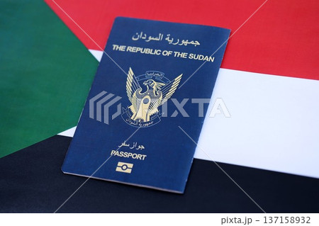 Sudanese passport on flag close up. Official identification document book for citizens of Sudan. Concept of travel and tourism 137158932