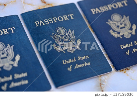 Three US passports on table close up. Official identification document books for citizens of United States. Concept of travel and tourism Three US passports on table close up. Official identification document books for citizens of United States. Concept of travel and tourism 137159030