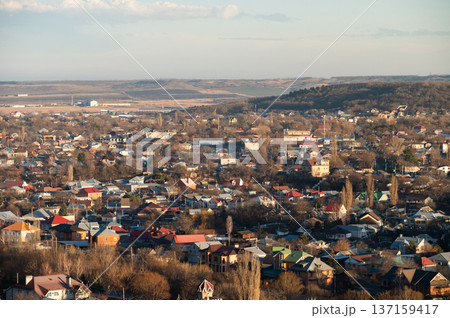 Aerial view of a rural town with diverse rooftops, trees, and fields under a clear sky, showcasing a blend of residential and agricultural landscapes Aerial view of a rural town with diverse rooftops, trees, and fields under a clear sky, showcasing a blend of residential and agricultural landscapes 137159417