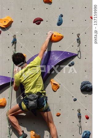 ボルダリングで壁を登る選手 137159990