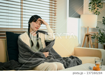 Young asian woman with headache or migraine sitting on sofa Young asian woman with headache or migraine sitting on sofa 137160284