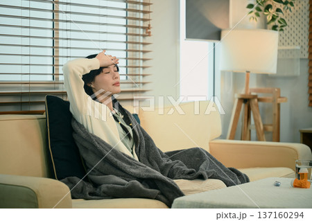 Young asian woman with headache or migraine sitting on sofa Young asian woman with headache or migraine sitting on sofa 137160294