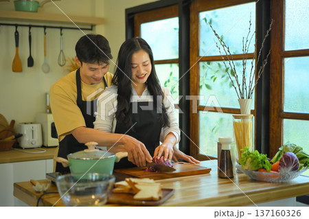 Couple cooking together at home, slicing fresh red cabbage on a wooden board 137160326