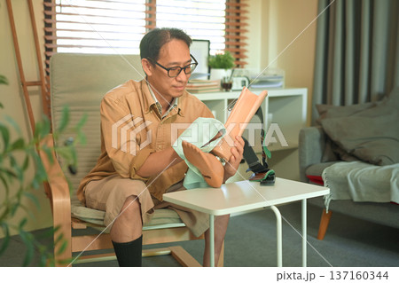 Middle aged man cleaning a prosthetic leg at home Middle aged man cleaning a prosthetic leg at home 137160344
