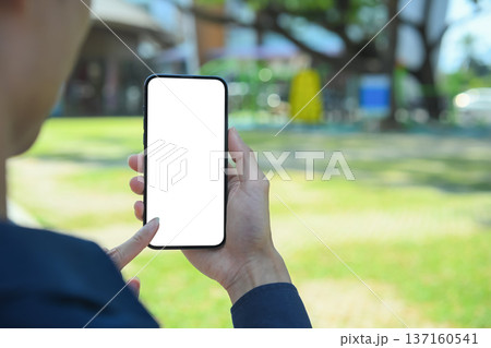 Hands holding smartphone with blank screen inside a modern community mall 137160541