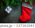 Christmas stocking and gift wrapped in silver surrounded by pine branches on a stone surface 137161043
