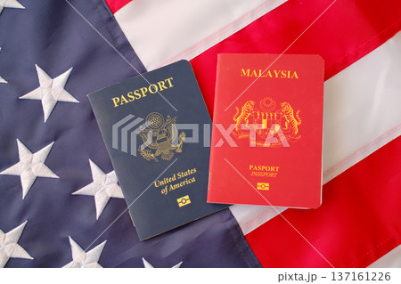 United States and Malaysia passports on American flag background, dual citizenship and international travel concept United States and Malaysia passports on American flag background, dual citizenship and international travel concept 137161226