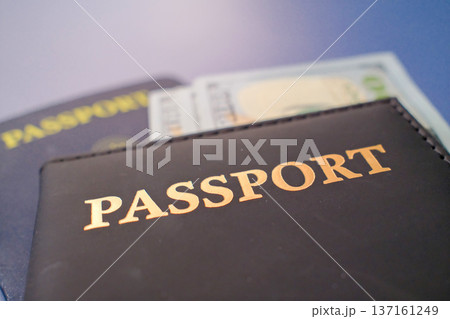 Passport in leather cover with dollar banknotes on blue background, travel finance and international journey concept closeup 137161249