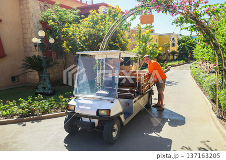 A man loads things into the back of a small electric car near his home A man loads things into the back of a small electric car near his home 137163205