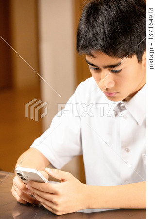 家でスマホを見る学生 137164918