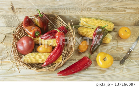 Freshly picked vegetables on rustic wooden table. Fresh harvest of peppers, corn and tomatoes in basket in kitchen. Freshly picked vegetables on rustic wooden table. Fresh harvest of peppers, corn and tomatoes in basket in kitchen. 137166097