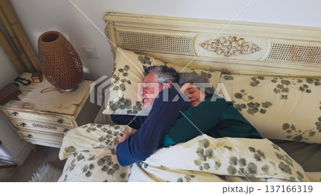 Senior couple sleeping together in bed hugging Senior couple sleeping together in bed hugging 137166319