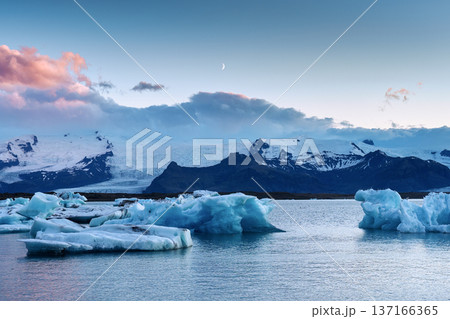 Blue iceberg floating in Jokulsarlon glacier lagoon with crescent moon in Iceland Blue iceberg floating in Jokulsarlon glacier lagoon with crescent moon in Iceland 137166365