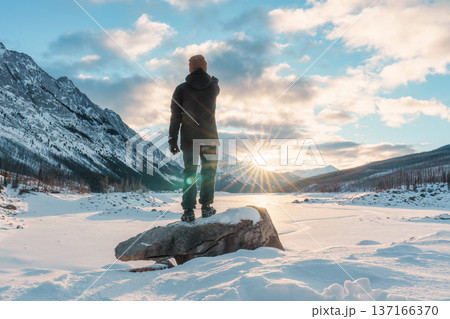 Adventurer man standing and pointing the rocky mountains and frozen lake at Medicine Lake, Canada Adventurer man standing and pointing the rocky mountains and frozen lake at Medicine Lake, Canada 137166370