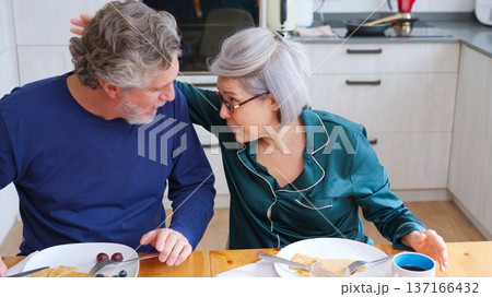Senior couple talking during breakfast in pajamas at home 137166432