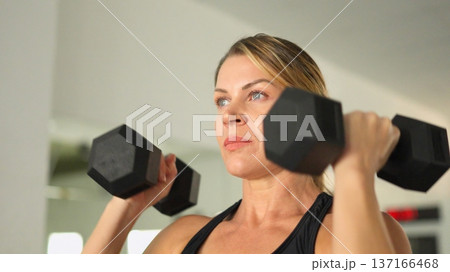 Woman exercising with dumbbells for strength training Woman exercising with dumbbells for strength training 137166468